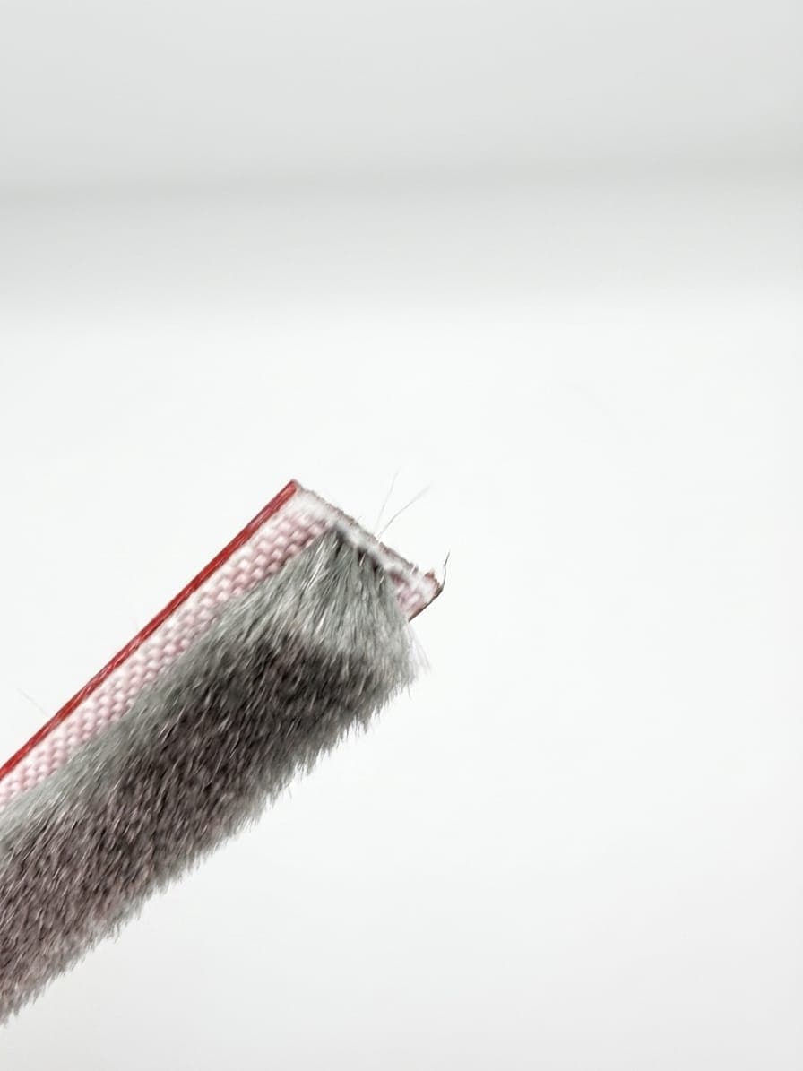 Self-adhesive pile weatherstrip with red adhesive backing tape